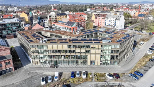 Luftaufnahme eines modernen Bürogebäudes mit Glasfassade in Kassel, umgeben von Parkplätzen und Wohnhäusern