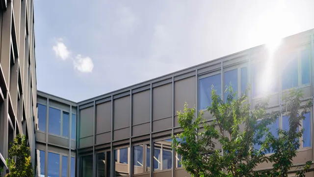 Gebäudefassade mit großen Fenstern und Sonneneinstrahlung im Hintergrund