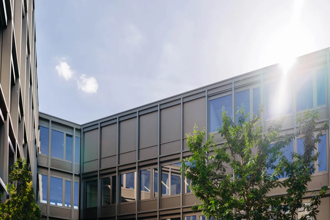 Gebäudefassade mit großen Fenstern und Sonneneinstrahlung im Hintergrund