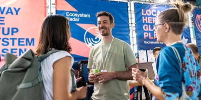 Aufnahme des StartHub Hessen-Stands auf dem Impact Festival 2024 in Frankfurt. Im Vordergrund sieht man den Gründer von Veli, der sich mit den Partnern der hessischen Start-up-Szene angeregt unterhält.
