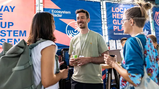 Aufnahme des StartHub Hessen-Stands auf dem Impact Festival 2024 in Frankfurt. Im Vordergrund sieht man den Gründer von Veli, der sich mit den Partnern der hessischen Start-up-Szene angeregt unterhält.