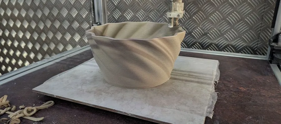 3D-Drucker fertigt spiralförmiges, schalenförmiges Objekt auf quadratischer Grundplatte