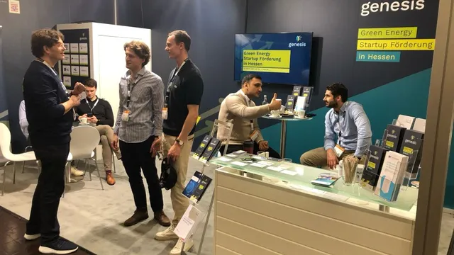Messestand mit fünf Personen, Informationsmaterial auf Theke und Wand mit Schriftzug 'genesis Green Energy Startup Förderung in Hessen'