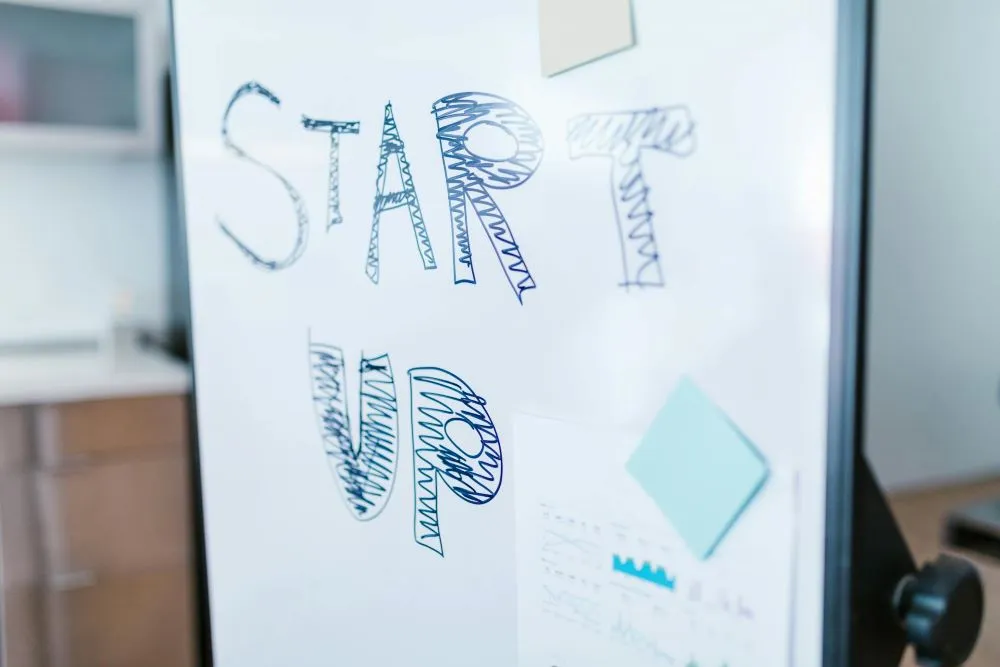 Auf einer weißen Tafel steht das Wort "Start-up"