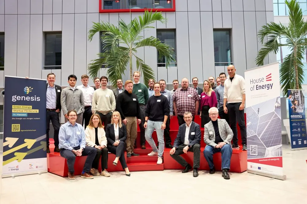 Gruppenfoto von Personen auf roten Stufen vor einer modernen Fassade mit zwei Roll-ups zu Green-Energy-Startups und House of Energy