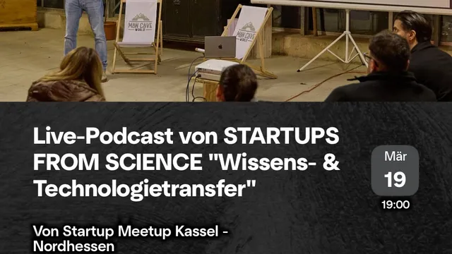 Person steht vor Leinwand mit Präsentation in einem Gewächshaus, Publikum sitzt auf Stühlen und Liegestühlen