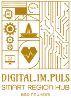 Goldfarbene Grafik mit Symbolen für künstliche Intelligenz, Zahnräder, Computer und Herz, daneben Leiterplattenmuster, darunter Schriftzug 'DIGITAL.IM.PULS SMART REGION HUB BAD NAUHEIM'.