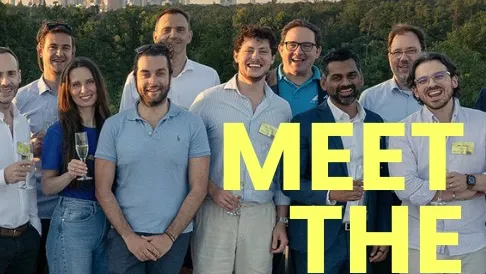 Gruppe von Menschen steht vor einer Stadtlandschaft mit Hochhäusern im Hintergrund und trägt lässige Kleidung