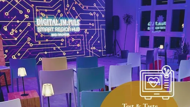 Moderner Veranstaltungsraum mit bunten Stühlen, kleinen Tischen und Lampen vor einer Wand mit leuchtendem Schriftzug 'DIGITAL.IM.PULS SMART REGION HUB' und einem Plakat mit Text zu einer Gesundheitsinnovation und Testveranstaltung am 12. März um 19 Uhr