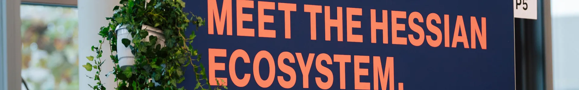 Aufnahme des StartHub Hessen-Stands auf dem Impact Festival 2024 in Frankfurt. Auf dem Bild ist zu lesen: "Meet the Hessian Ecosystem" / Triff die hessische Start-up-Szene