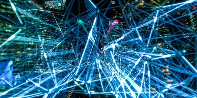 Leuchtende blaue Linien und Punkte bilden ein komplexes Netzwerk vor einer nächtlichen Stadtkulisse mit Hochhäusern.