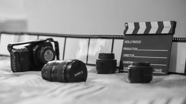 Schwarz-weiße Nahaufnahme von Filmkamera, Kameraobjektiven, Filmklappe und Filmstreifen auf einer Oberfläche