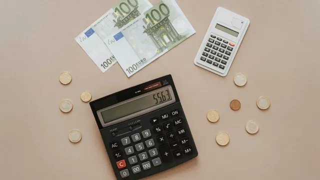 Zwei Taschenrechner, drei 100-Euro-Scheine und mehrere Euro-Münzen auf hellem Untergrund