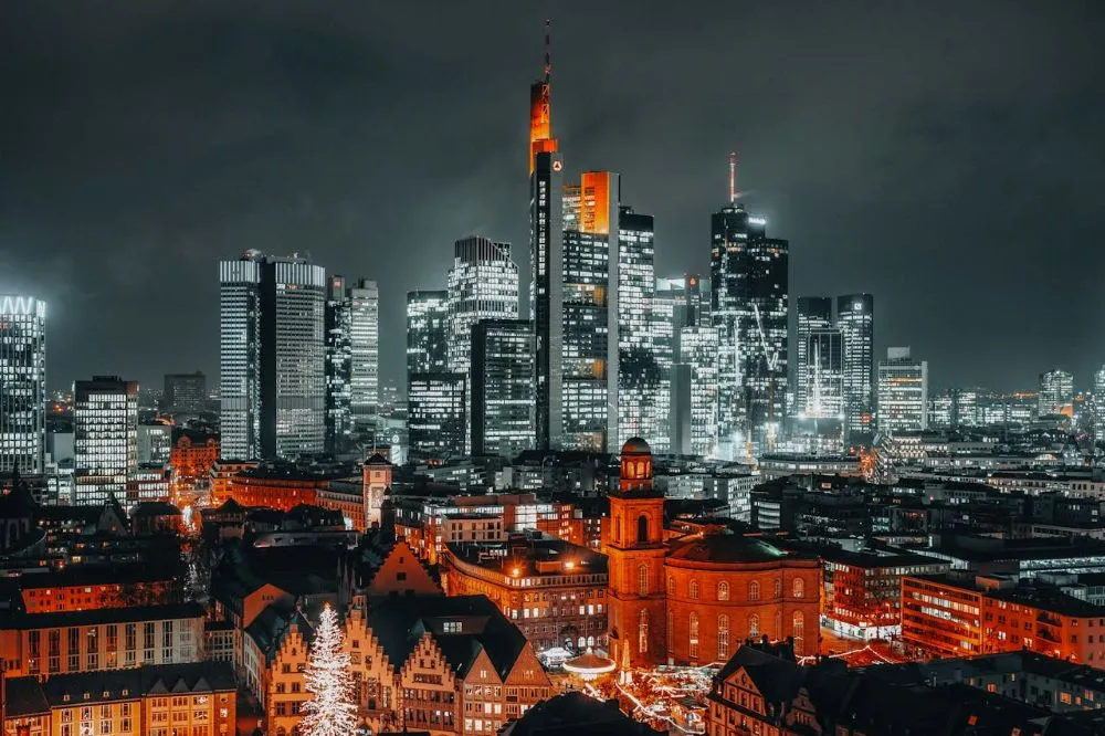 Nächtliche Skyline von Frankfurt mit beleuchteten Hochhäusern und historischen Gebäuden im Vordergrund
