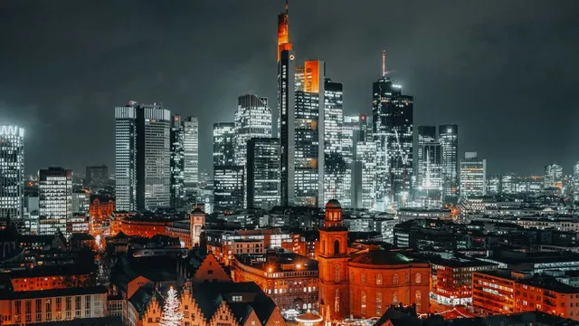Nächtliche Skyline von Frankfurt mit beleuchteten Hochhäusern und historischen Gebäuden im Vordergrund