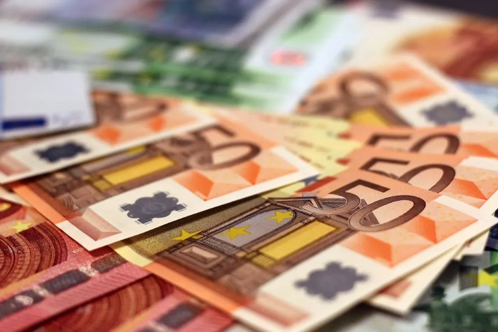 Mehrere 50-Euro-Scheine liegen übereinander, im Hintergrund unscharfe Euro-Banknoten verschiedener Werte.