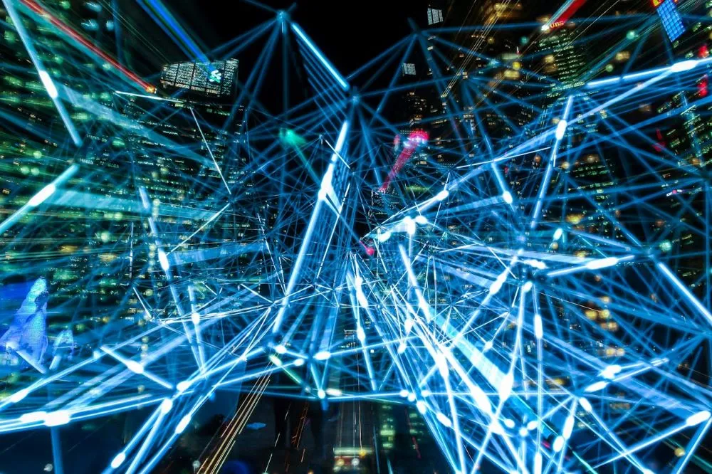 Netzwerk aus leuchtenden Linien über einer nächtlichen Stadt mit Hochhäusern, symbolisiert künstliche Intelligenz