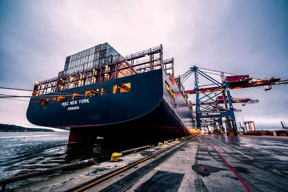 Containerschiff MSC New York aus Panama am Hafen mit Containern und Kränen bei bewölktem Himmel