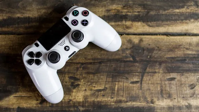 Weißer PlayStation-Controller mit schwarzen Tasten auf rustikalem Holztisch