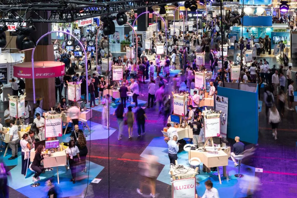 Große Messehalle mit zahlreichen Ständen und vielen Besuchern, die sich zwischen den Ausstellungsflächen bewegen