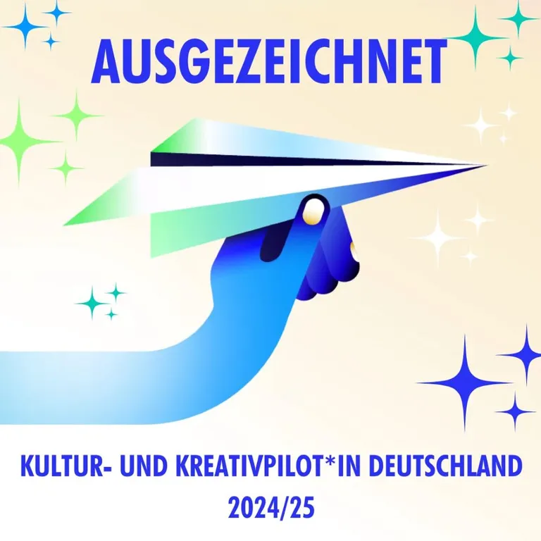 Auszeichnung der Kultur- und Kreativpiloten wurde vergeben. Auf dem Bild ist eine blaue Hand zu sehen, die einen Papierflieger hält.